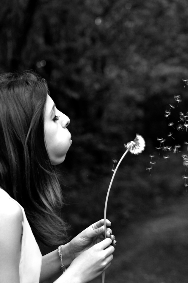 woman blowing a dandelion